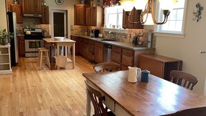 A spacious kitchen with wooden cabinets, a central island, and a dining area with chairs. - Country Quiet 3 Bedroom 2 Bath Tranquil Space! (Millsboro)