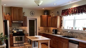 A kitchen with wooden cabinets, a stainless steel stove, a sink, and a window with a curtain. - Country Quiet 3 Bedroom 2 Bath Tranquil Space! (Millsboro)