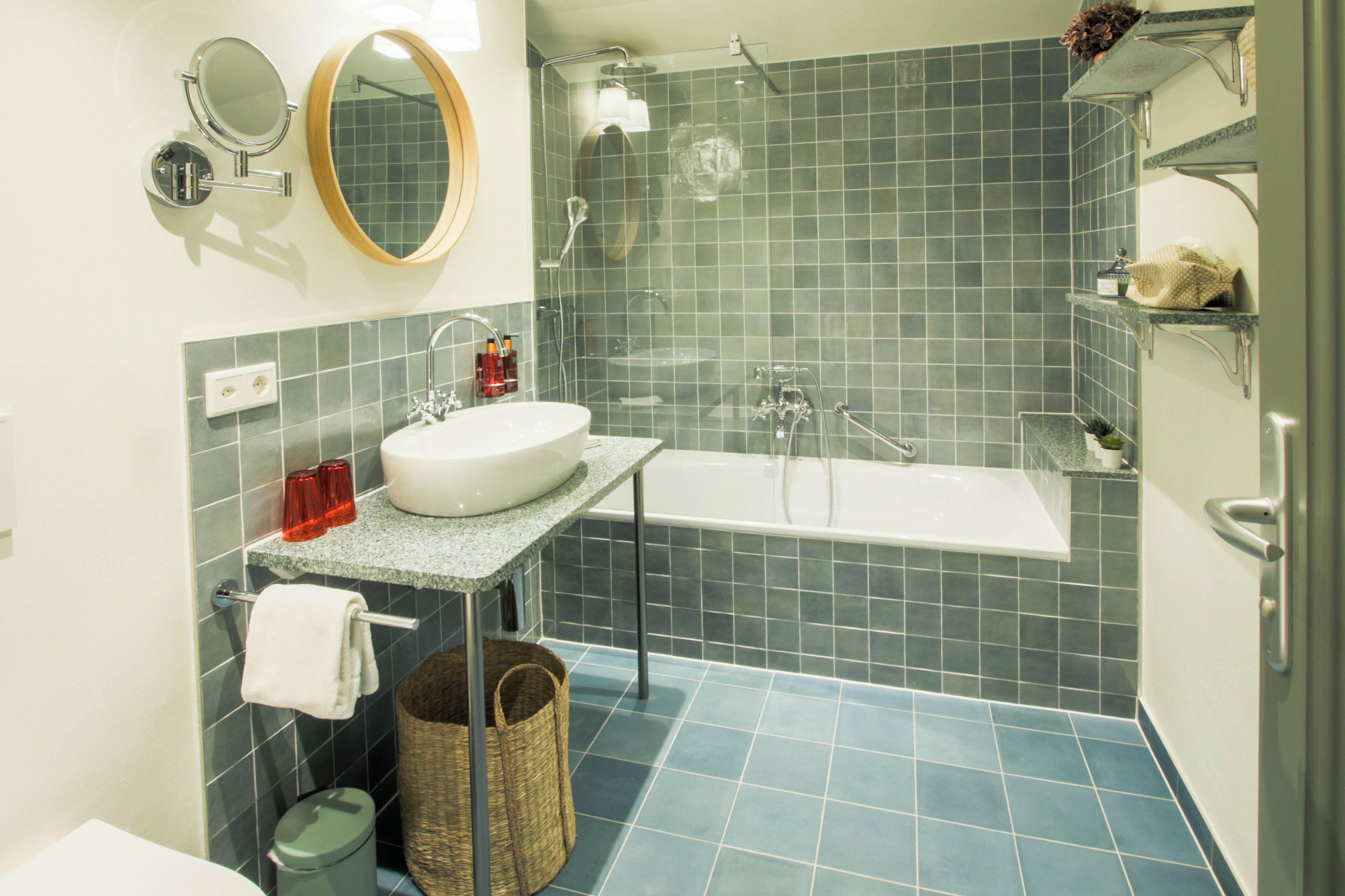 A bathroom with a white bathtub, a sink with a granite countertop, and a mirror above the sink.