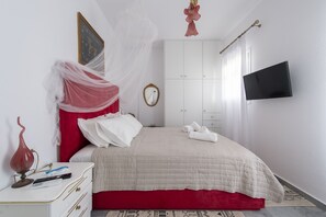 Quarto com cama, mesa de cabeceira, guarda-roupa, televisão e um objeto decorativo.