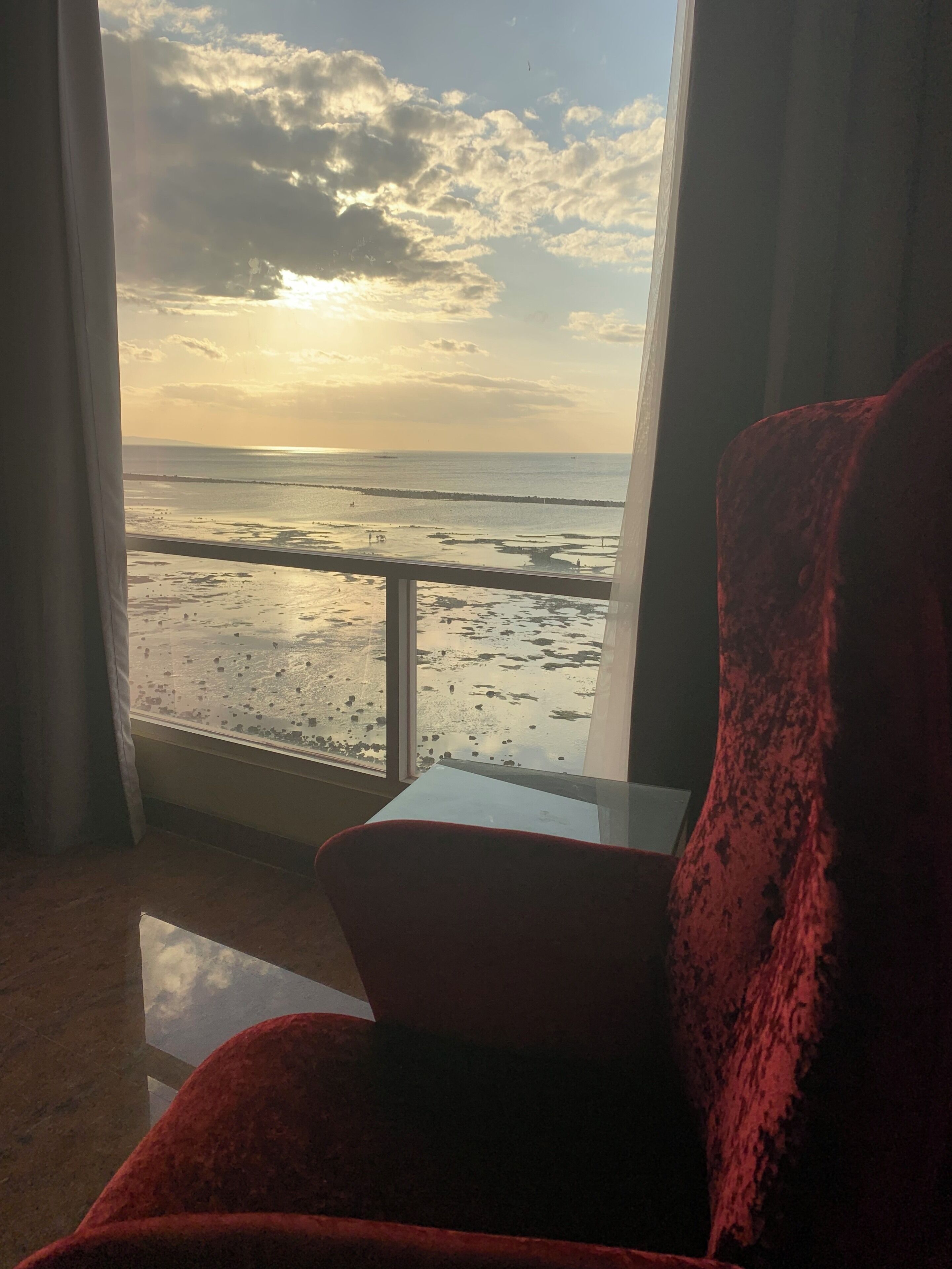 Een kamer met uitzicht op het strand en de oceaan door grote ramen.