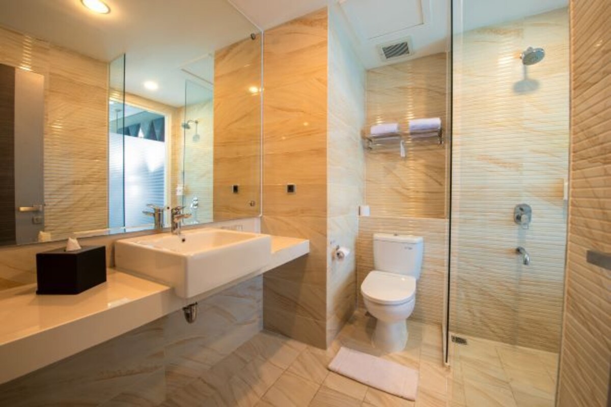 Een moderne badkamer met een douchecabine van glas, een witte wastafel en een toilet.