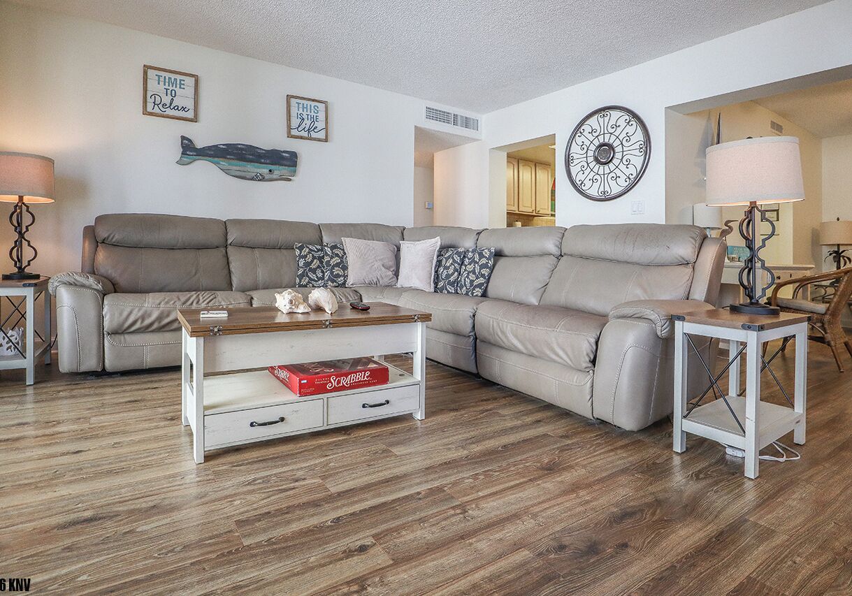 A living room with a sectional sofa, a coffee table, a side table, and wall art.