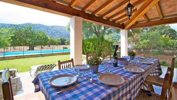 An outdoor dining area with checkered tablecloths, wooden chairs, and a view of a swimming pool and mountains. - Finca Can Pontico - Four Bedroom House, Sleeps 6 (Pollensa)