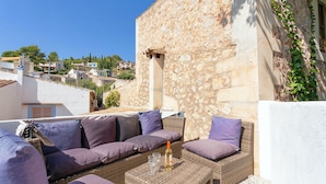 A rooftop terrace with wicker furniture, a bottle of wine, and a view of the surrounding neighborhood. - Casa Pont Roma, Private Pool, walk to restaurants (Pollença)