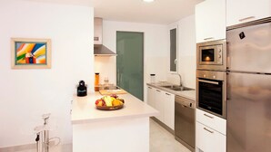 Una cucina moderna con elettrodomestici in acciaio inossidabile, un'isola centrale con frutta e una porta verde sullo sfondo.