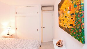Una camera da letto con un letto, un comodino, un quadro appeso al muro e una porta.