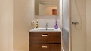 Une salle de bain avec un lavabo blanc, un miroir et une douche.