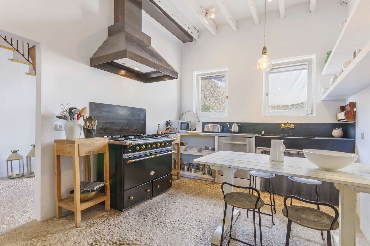 A kitchen with a large stove, wooden table, and bar stools.