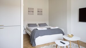 A modern bedroom with a bed, bedside table, and a small white table with a decorative bowl. - 2ndhomes Ullanlinna Penthouse Apartments 2 (Helsinki)