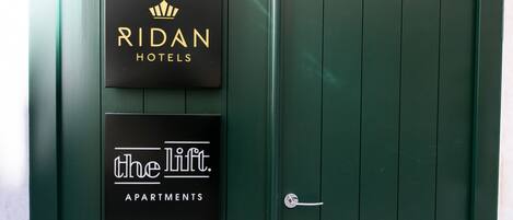 Dos carteles en una puerta verde: "RIDAN HOTELS" y "ascensor. APARTAMENTOS".