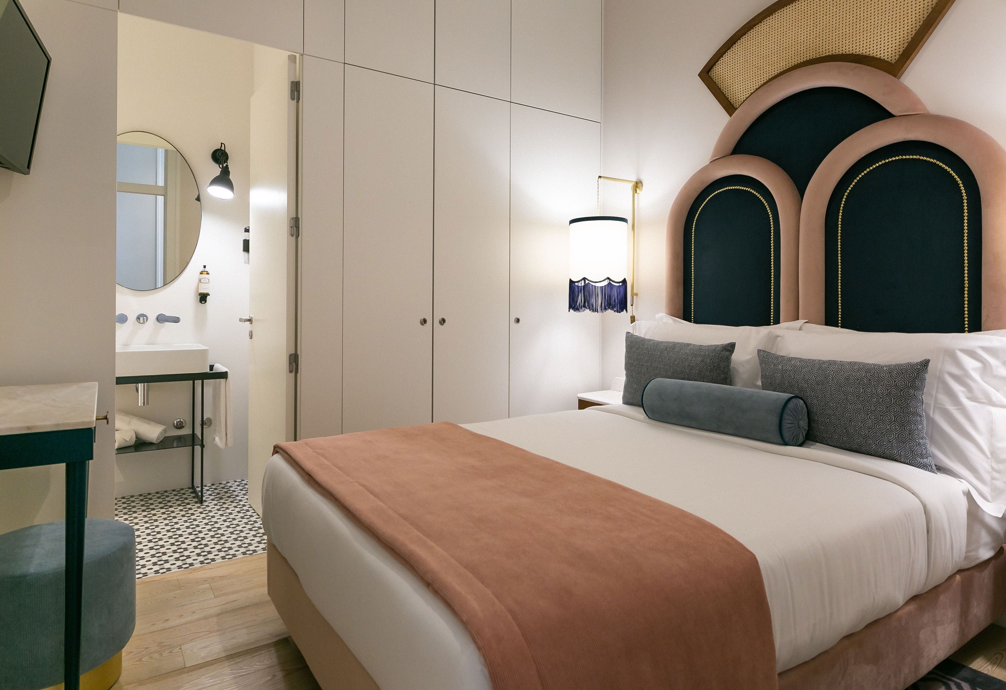 A modern bedroom with a large bed, a bedside table, a mirror, and a wardrobe.