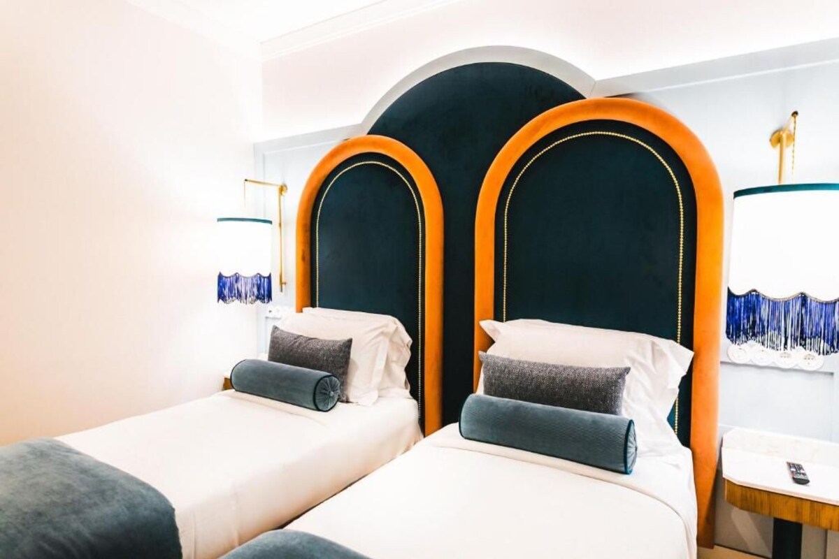 A hotel room with two beds, each with a headboard and pillows.