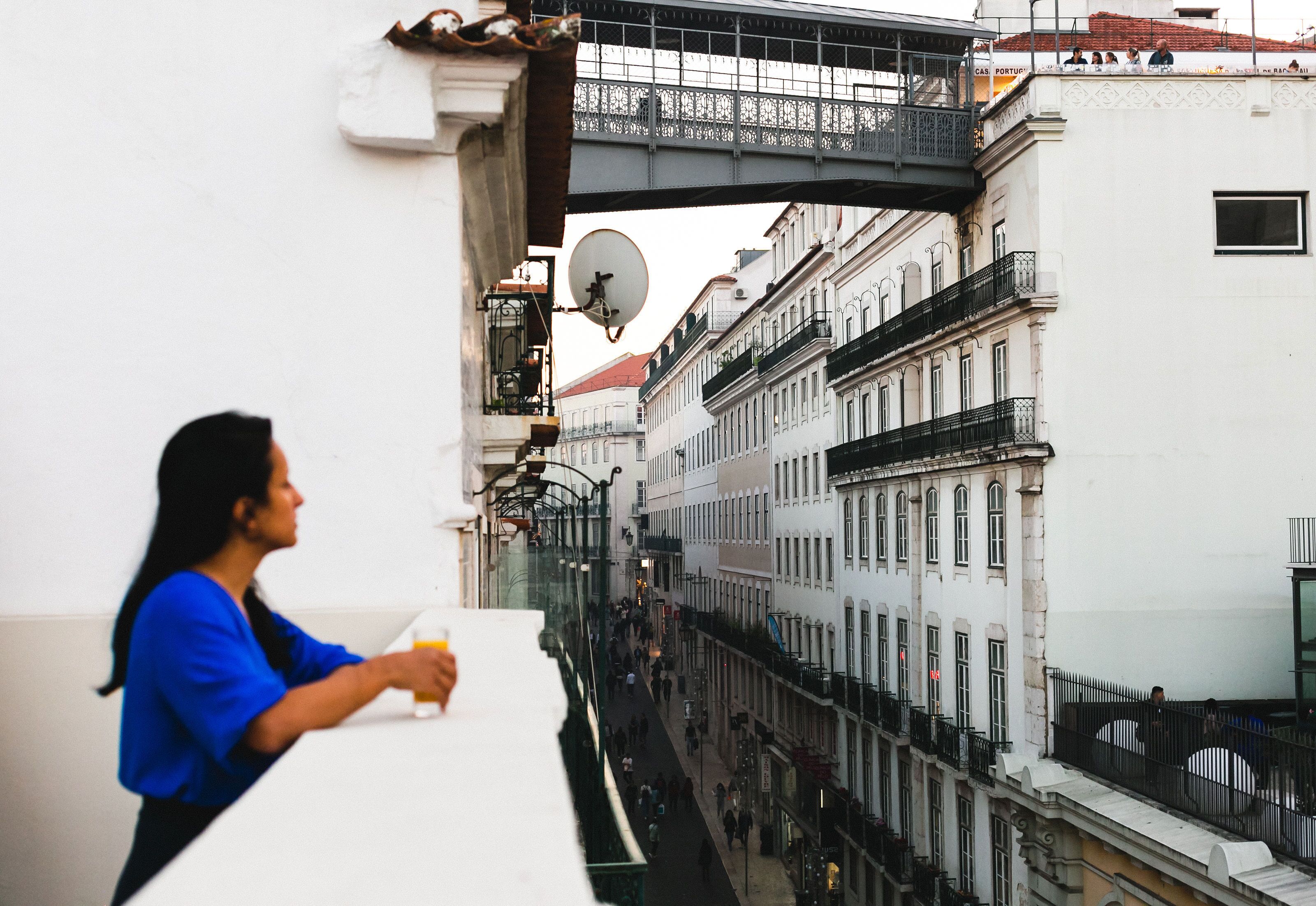 Una calle urbana estrecha flanqueada por edificios, con una acera peatonal y un puente sobre ella.