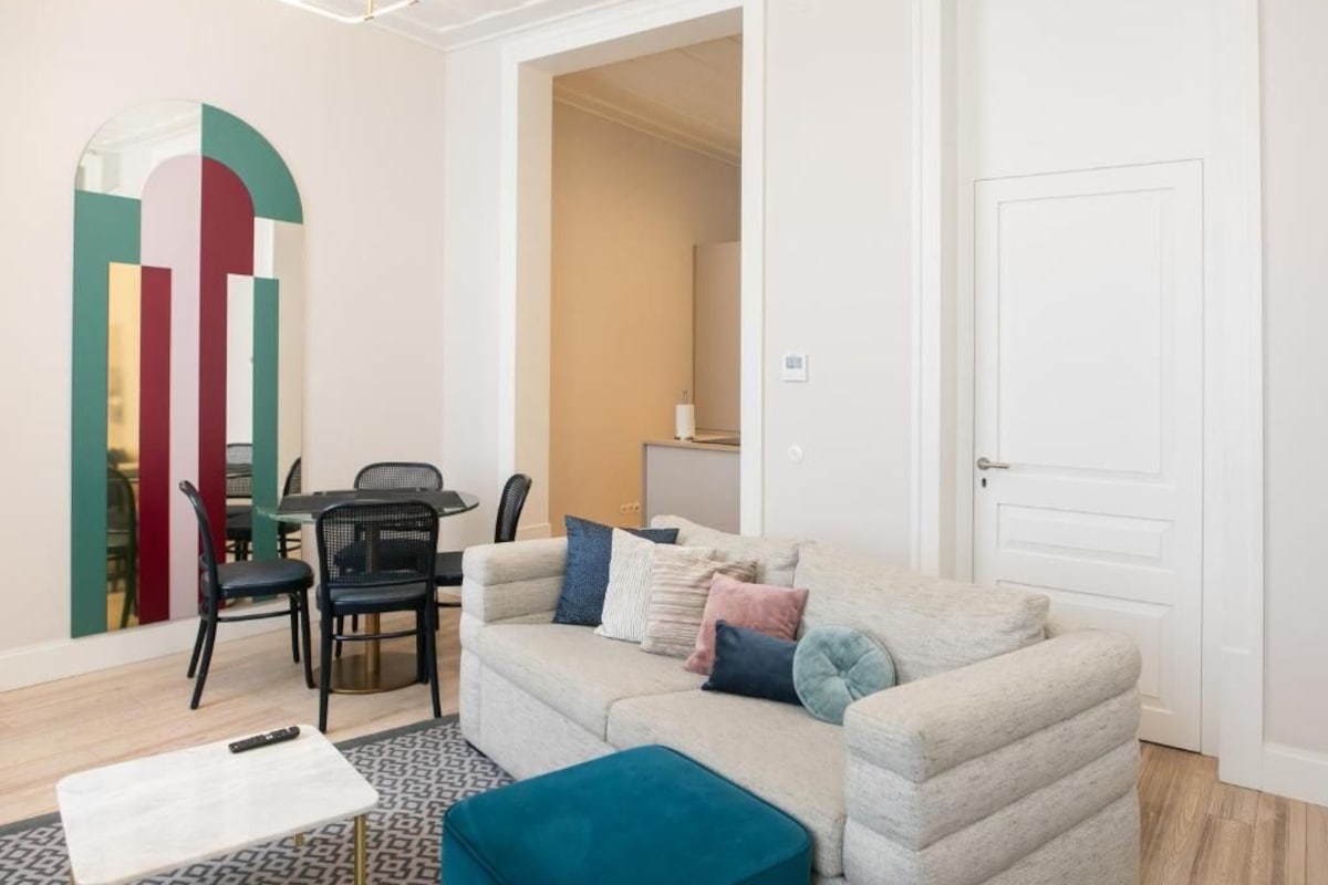 A modern living room with a sofa, a coffee table, and a dining area with chairs and a table.
