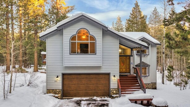 A two-story house with a wooden garage door, a front porch with a bench, and a staircase leading to the entrance. - Backs to National Forest!  Trails just outside your Door - Stunning!  1801J (South Lake Tahoe)