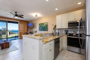 A modern kitchen with a large island, stainless steel appliances, and a view of the ocean.