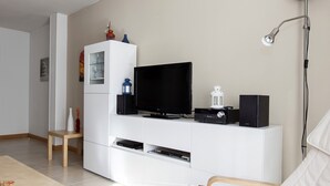Una sala de estar moderna con un mueble blanco para entretenimiento, un televisor de pantalla plana y una lámpara de pie.