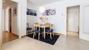 Un comedor con una mesa y sillas, un jarrón con flores secas y cuadros en la pared.