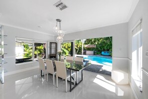 Una cocina moderna con zona de comedor de vidrio que da a una piscina.