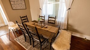 Uma sala de jantar com uma mesa de madeira, quatro cadeiras, um banco e uma placa decorativa na parede.