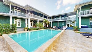 A pool area with a two-story building, outdoor seating, and a staircase leading to the upper level. - Saint Patrick Palace - Wedding-Ready Luxury Estate w/ Pool & Guest Cottage (Davie)