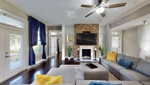 A spacious living room with a fireplace, a ceiling fan, and a large TV mounted on the wall. - Saint Patrick Palace - Wedding-Ready Luxury Estate w/ Pool & Guest Cottage (Davie)