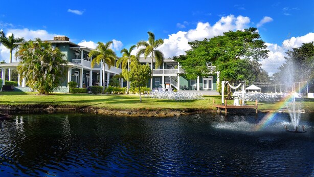 A large building with a pool, palm trees, and a fountain. - Saint Patrick Palace - Wedding-Ready Luxury Estate w/ Pool & Guest Cottage (Davie)