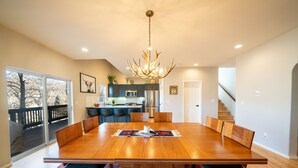 Un comedor espacioso con una gran mesa de madera, asientos cómodos y una lámpara moderna.