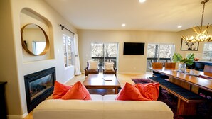 Un salón amplio con chimenea, un espejo grande y un comedor con mesa y sillas de madera.