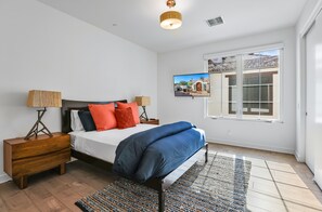 Un dormitorio con cama, mesitas de noche, televisor y ventana con vistas.