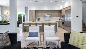 Una cocina moderna con una isla central, electrodomésticos integrados y un comedor con sillas.