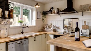 Een keuken met een vaatwasser, houten aanrecht, een spoelbak en een wijnfles.