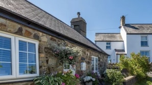 A stone building with a gravel pathway, potted plants, and a clear blue sky.