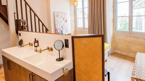 A modern bathroom with a large sink, a mirror, and a towel rack. There is a window with curtains and a view of a building outside. - LOLA Boutique Hôtel Bordeaux Centre (Bordeaux)