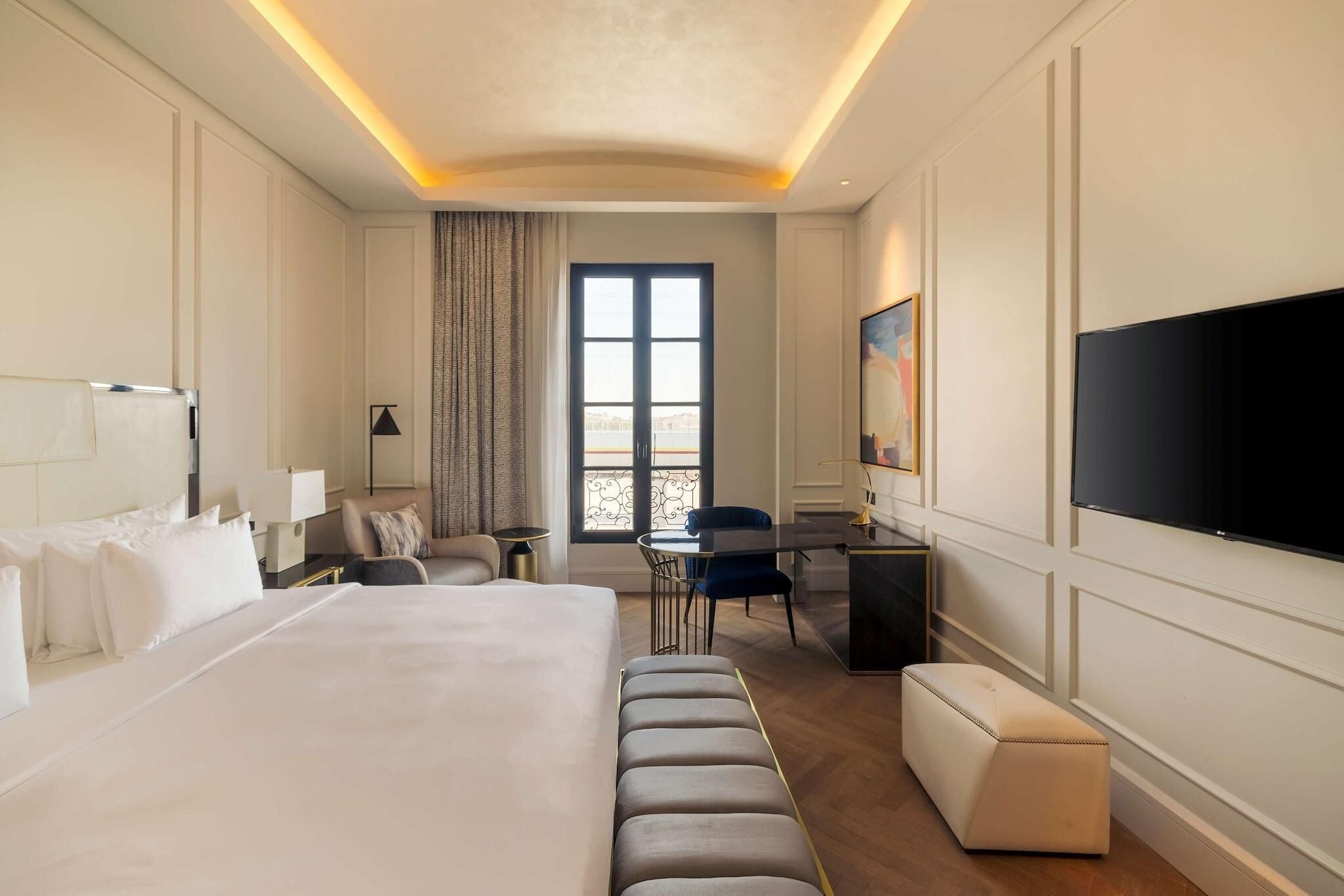 Ein Hotelzimmer mit einem großen Bett, einem Schreibtisch, einem Stuhl, einem Fernseher und einem Fenster mit Blick.