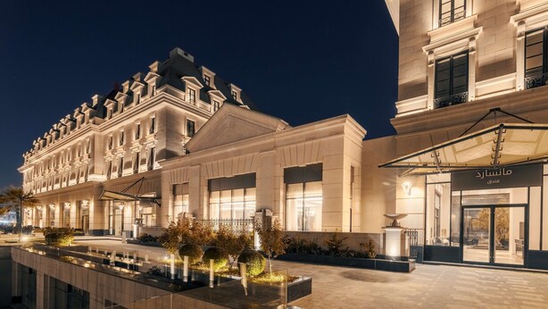 Un hotel elegante de arquitectura clásica, con un amplio patio y una entrada bien iluminada.