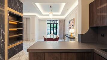 A modern kitchen with a central island, built-in shelving, and a dining area with a round table and chairs.