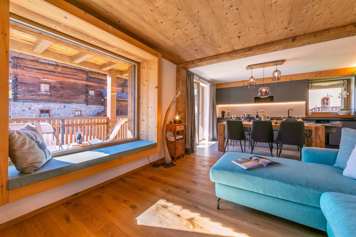 A cozy cabin interior with a dining area, a seating area with a view, and a kitchen.
