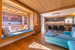 A cozy cabin interior with a dining area, a seating area with a view, and a kitchen.