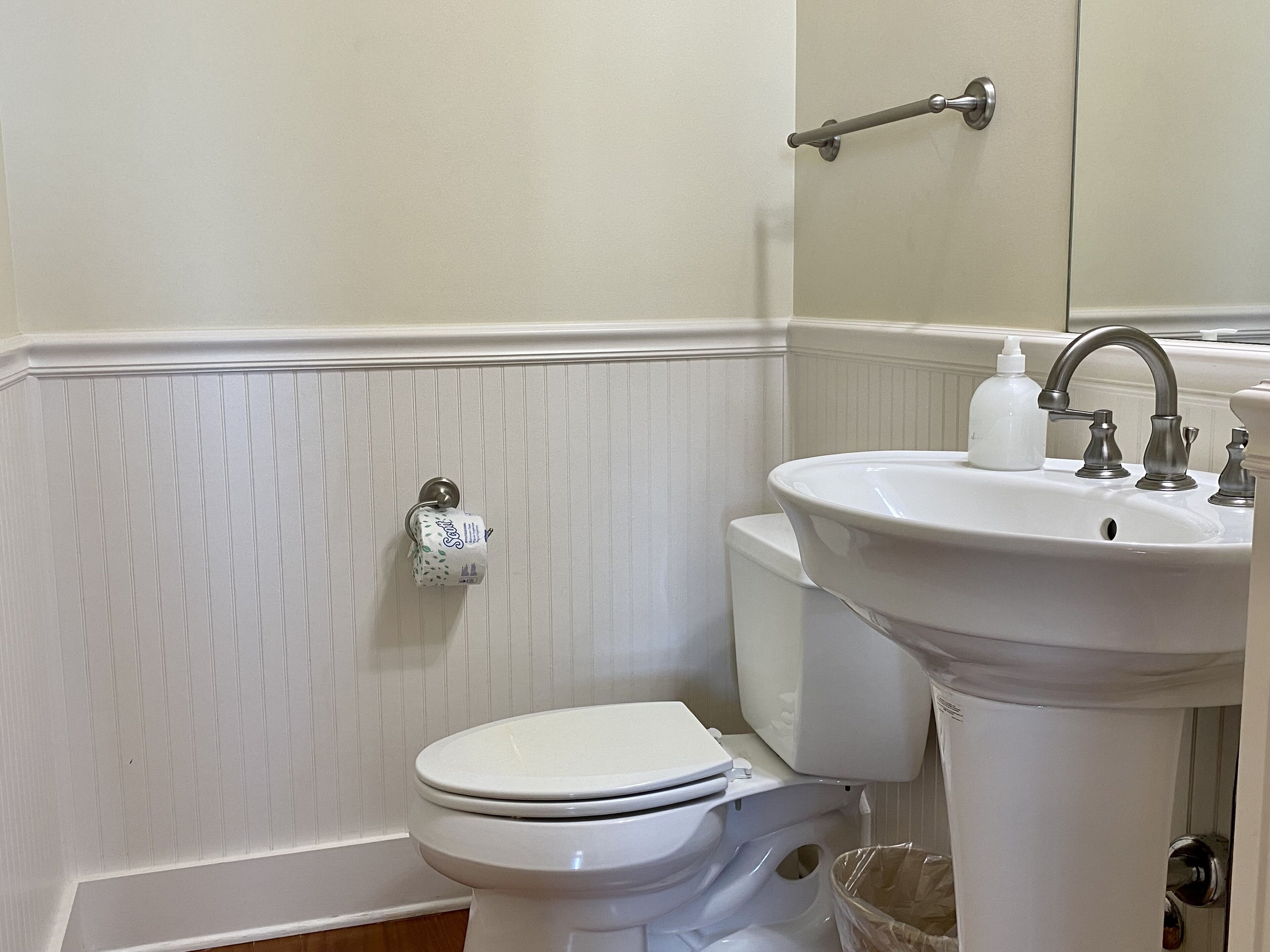 A bathroom with a toilet, sink, and towel rack.