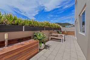 Une terrasse sur le toit, avec un banc en bois, une table et des plantes en pot.