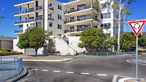 A multi-story residential building with balconies, a roundabout, and a traffic sign. - Carrington Nelson Bay (Nelson Bay)