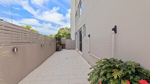 Pathway leads to the entrance of a modern building with a flat roof and large windows.