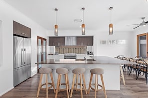 A modern kitchen with a central island, stainless steel appliances, and a dining area with bar stools.