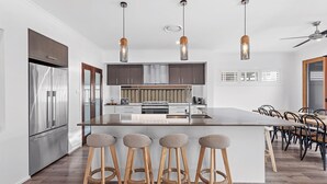 A modern kitchen with a central island, stainless steel appliances, and wooden bar stools.
