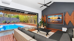 A modern living room with a pool, grey walls, and a large framed picture of a beach scene.
