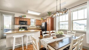 Una cocina moderna con armarios de madera, una isla central y un comedor con mesa y sillas.