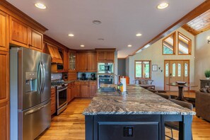 Enjoy cooking in this well-equipped kitchen with a large island, stainless steel appliances, and a view of the outdoors.