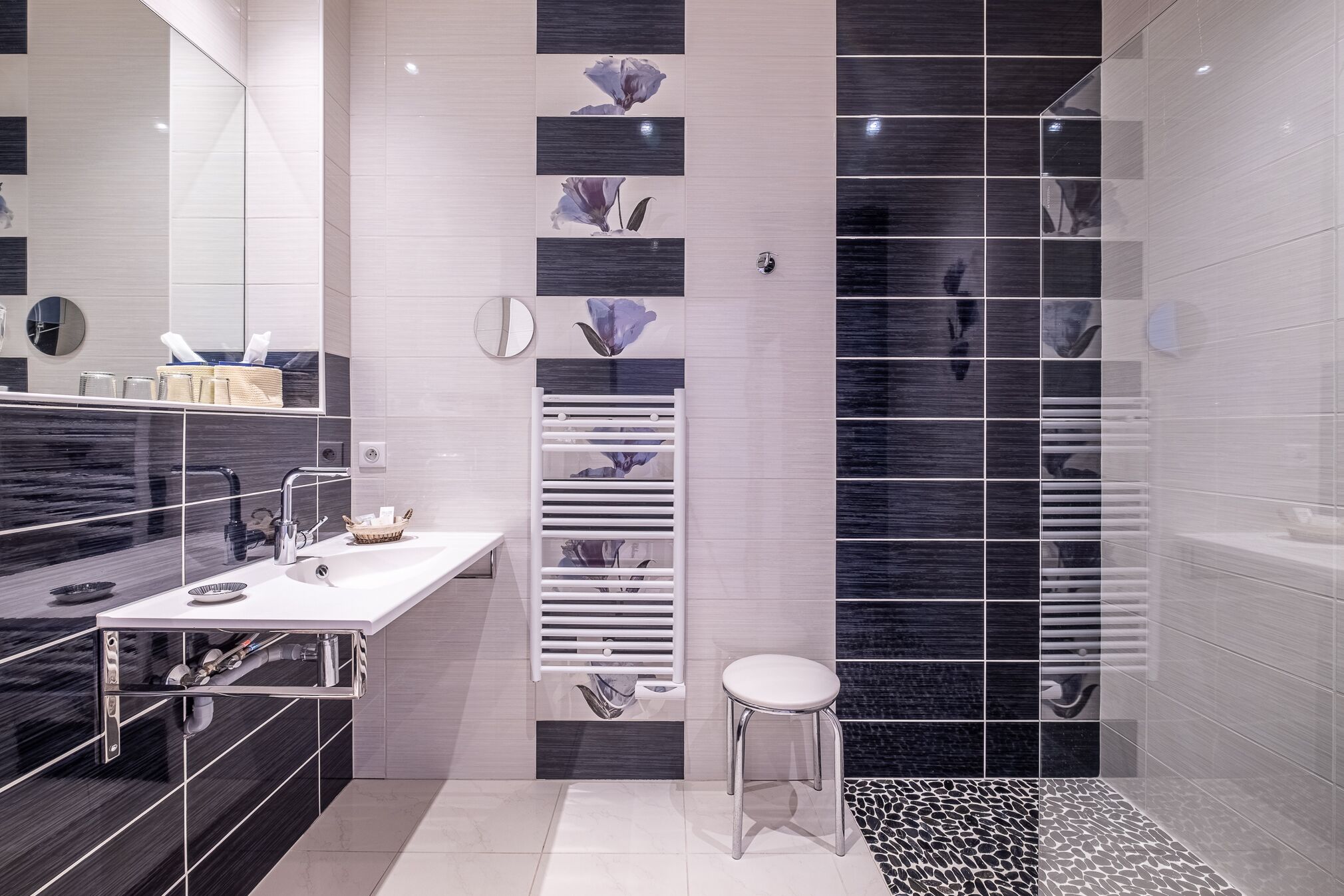 A modern bathroom with a large mirror, a white sink, and a shower area.